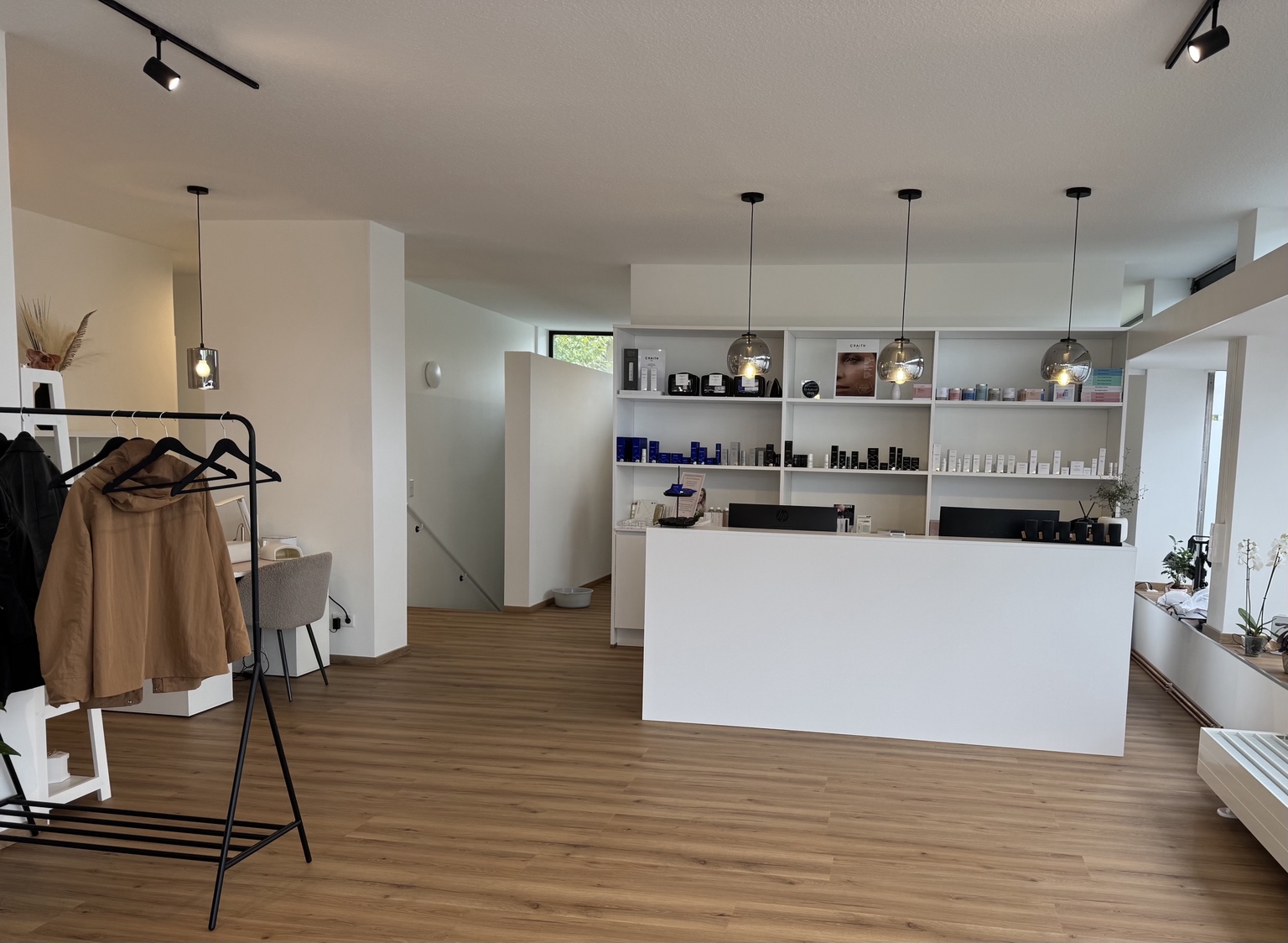 Heller Empfang im Beautyloft mit weißer Theke und Produktregalen