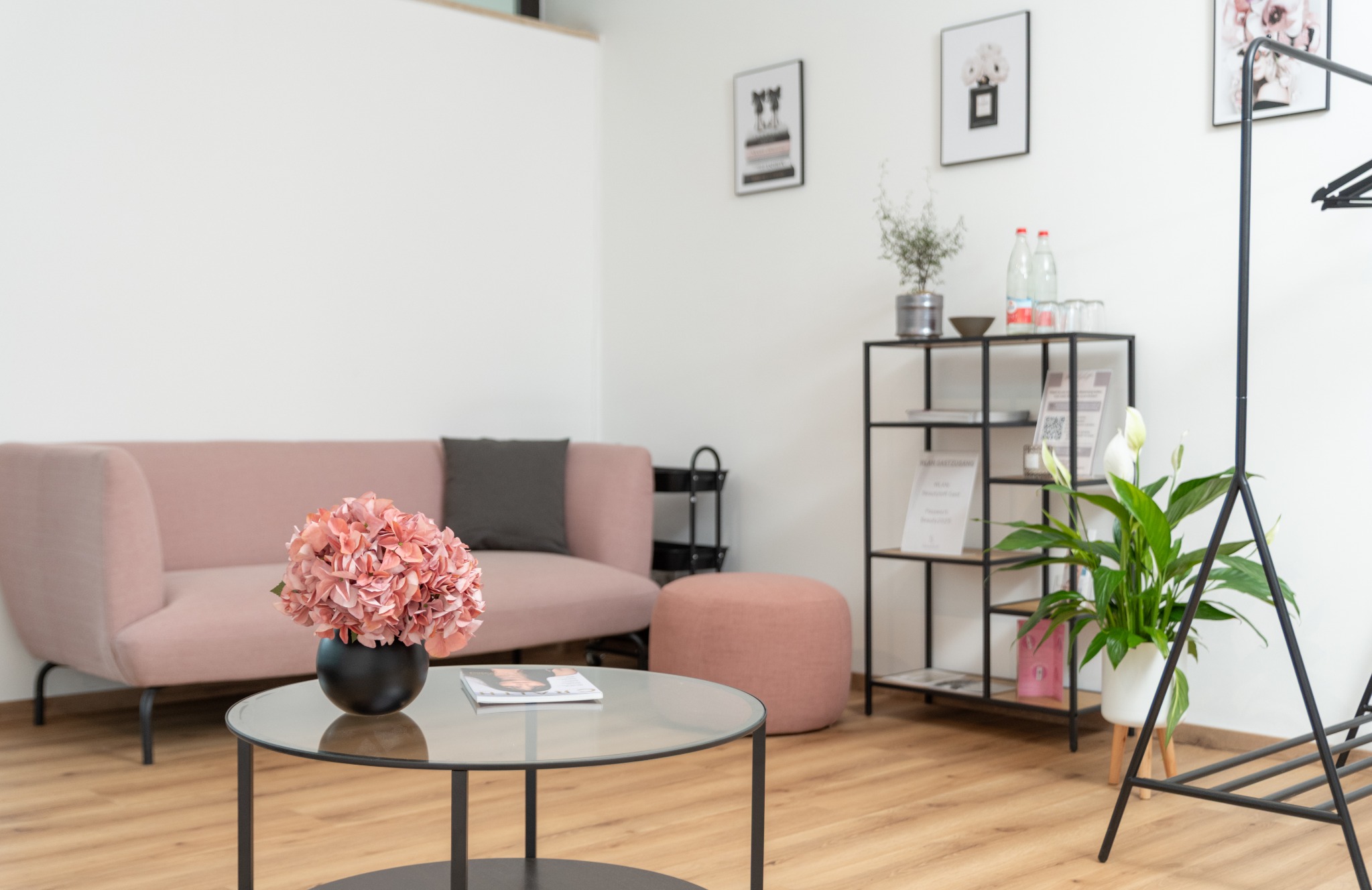 Wartebereich im Beautyloft mit rosa Sofa, Glastisch und Blumen
